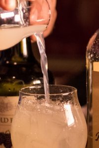 Cocktail being poured into a tulip glass